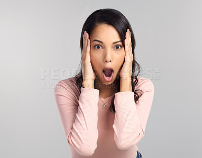 Buy stock photo Shot of a beautiful young woman looking shocked while standing against a grey background