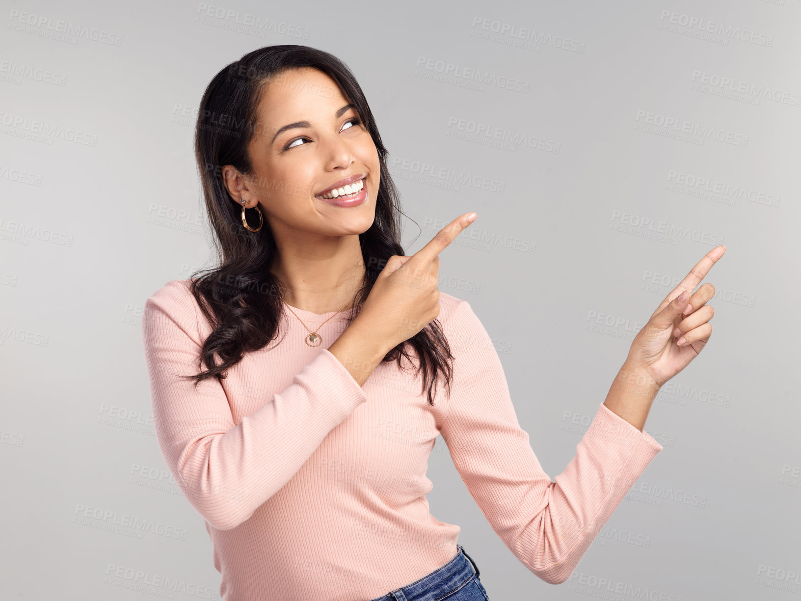 Buy stock photo Shot of a beautiful young woman pointing at copy space