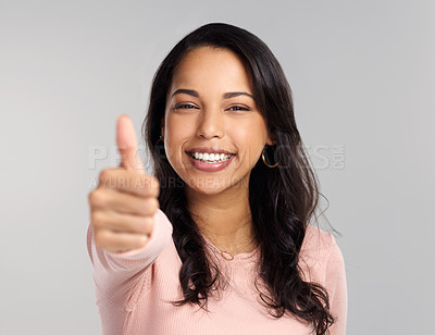 Buy stock photo Shot of a beautiful young woman showing thumbs up while standing against a grey background