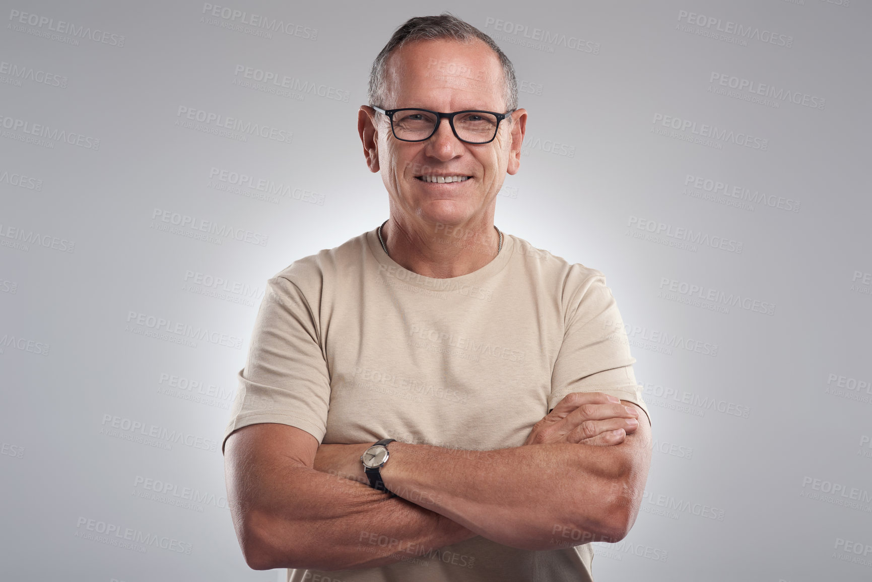 Buy stock photo Shot of a handsome mature man standing alone against a grey background in the studio with his arms folded