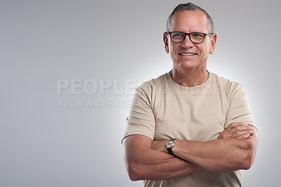 Buy stock photo Shot of a handsome mature man standing alone against a grey background in the studio with his arms folded