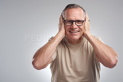 Buy stock photo Shot of a mature man standing against a grey background in the studio and covering his ears with his hands