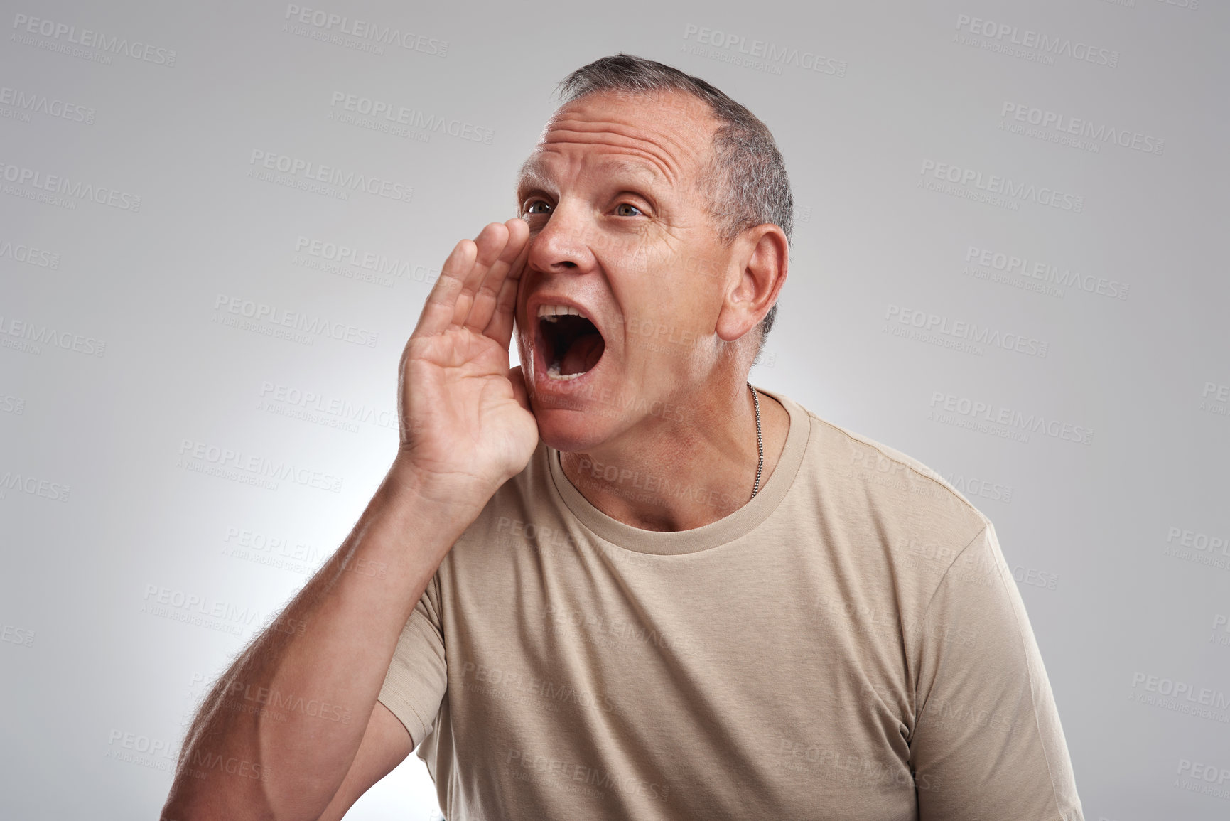 Buy stock photo Shot of a handsome mature man standing alone against a grey background in the studio and shouting