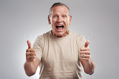 Buy stock photo Shot of a handsome mature man standing against a grey background in the studio and making a thumbs up gesture