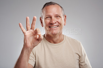 Buy stock photo Shot of a handsome mature man standing against a grey background in the studio and making an okay hand gesture