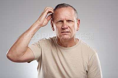 Buy stock photo Shot of a handsome mature man standing against a grey background in the studio and scratching his head in confusion