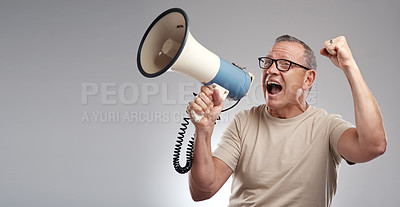 Buy stock photo Shot of a handsome mature man standing alone against a grey background in the studio and using a megaphone