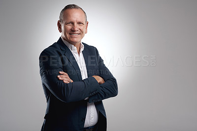 Buy stock photo Shot of a handsome mature businessman standing alone against a grey background in the studio with his arms folded