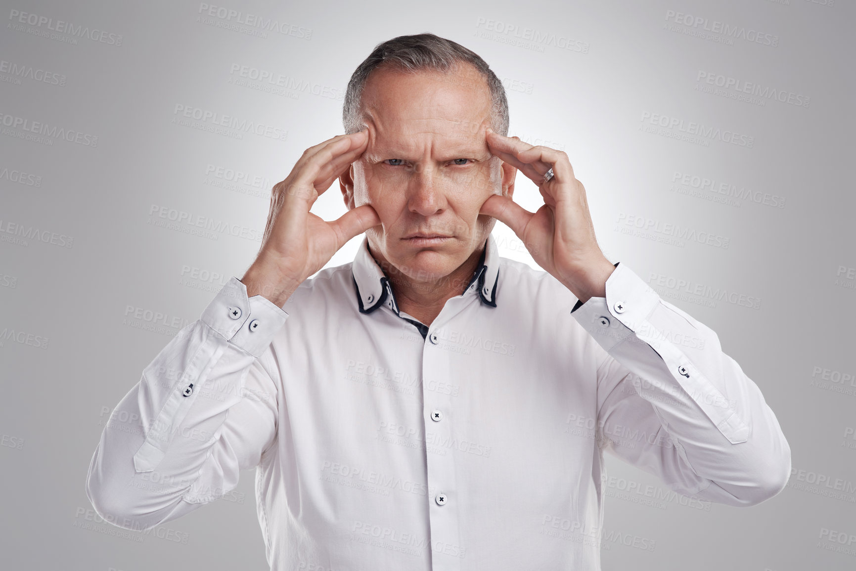 Buy stock photo Shot of a handsome mature businessman standing alone against a grey background in the studio and feeling stressed