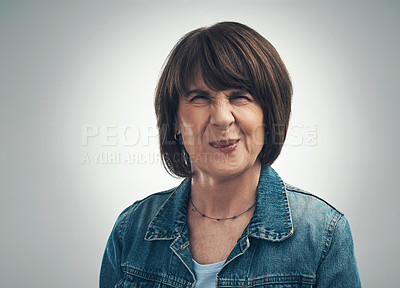 Buy stock photo Studio portrait of a senior woman frowning against a grey background