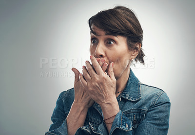 Buy stock photo Studio shot of a senior woman covering her mouth and looking shocked against a grey background