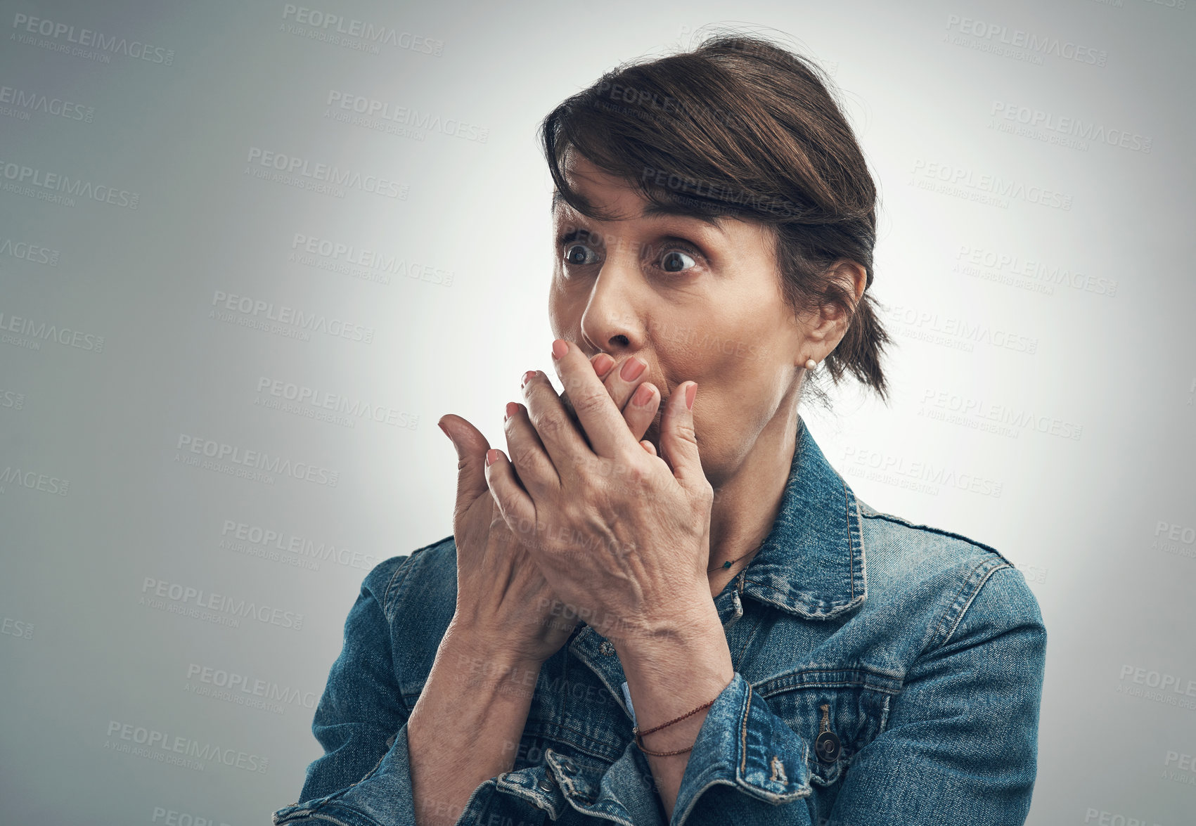 Buy stock photo Studio shot of a senior woman covering her mouth and looking shocked against a grey background