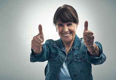 Buy stock photo Studio portrait of a senior woman showing thumbs up against a grey background