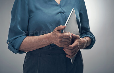 Buy stock photo Studio shot of an unrecognisable woman holding a digital tablet against a grey background