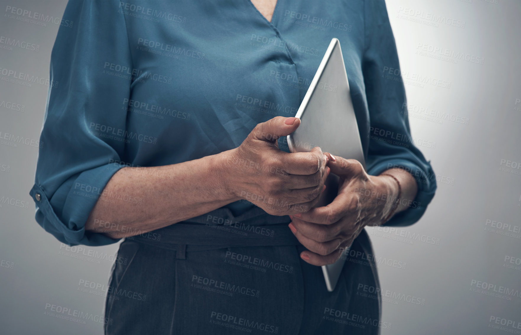 Buy stock photo Studio shot of an unrecognisable woman holding a digital tablet against a grey background