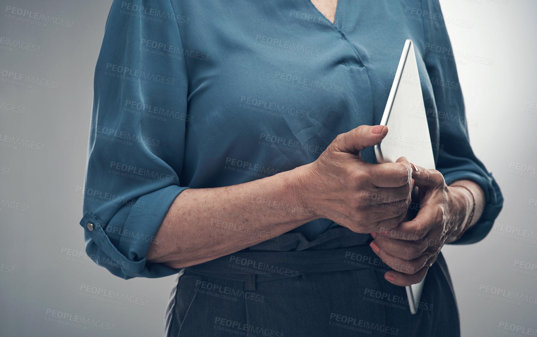 Buy stock photo Studio shot of an unrecognisable woman holding a digital tablet against a grey background