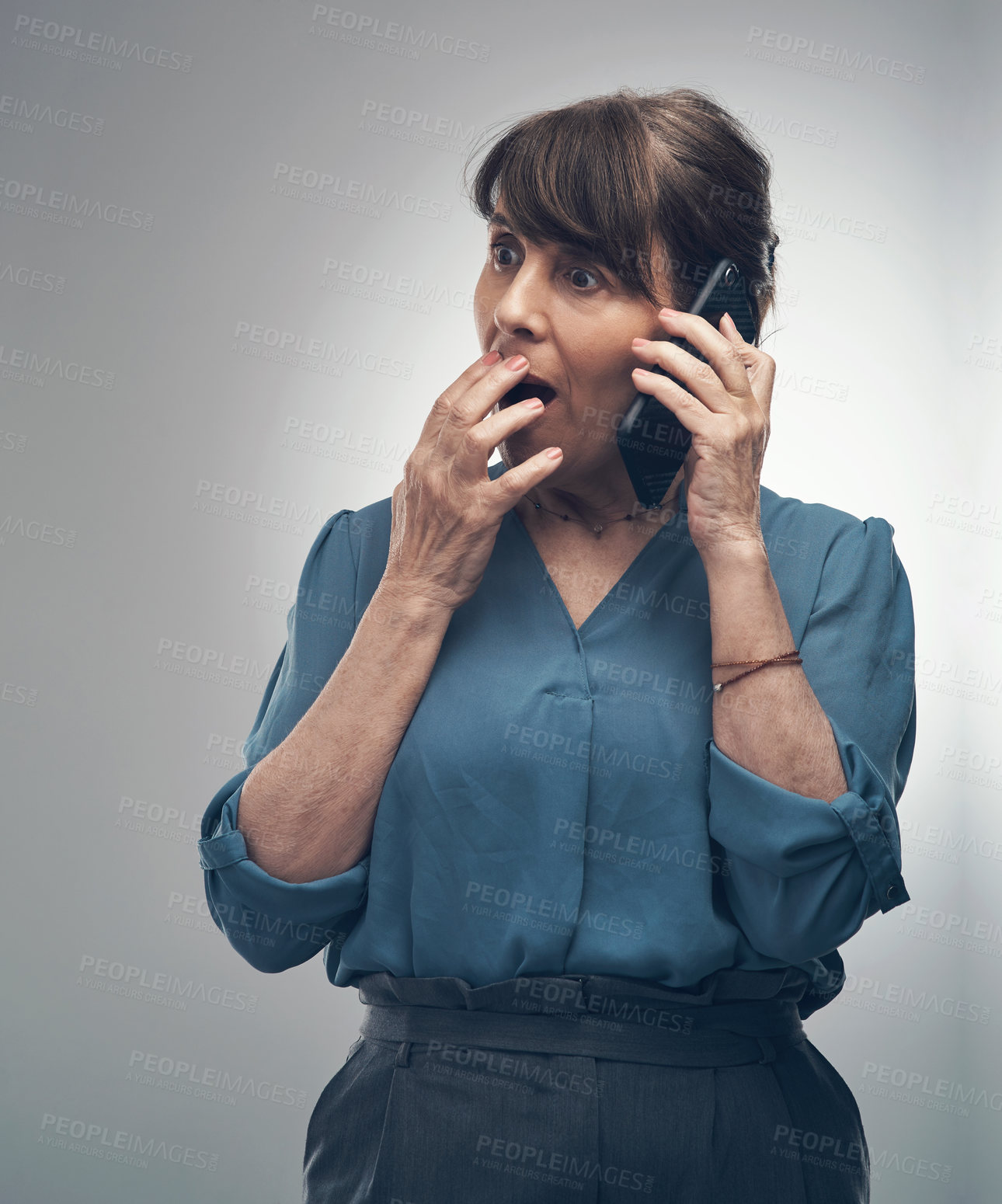 Buy stock photo Studio shot of a senior woman looking shocked while talking on a cellphone against a grey background