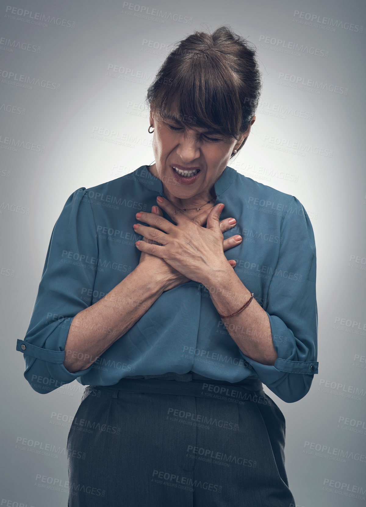 Buy stock photo Studio shot of a senior woman holding her chest in pain against a grey background