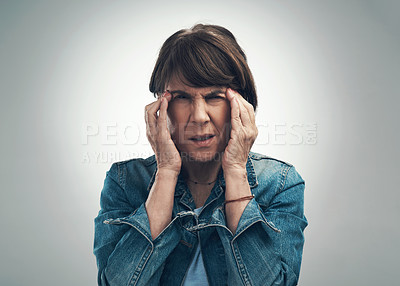 Buy stock photo Studio portrait of a senior woman experiencing a headache against a grey background