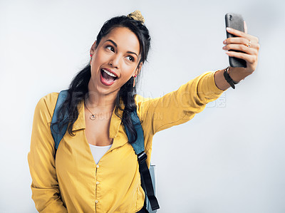 Buy stock photo Studio shot of a woman wearing a backpack and taking selfies against a white background