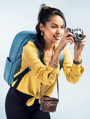 Buy stock photo Shot of a young woman wearing a backpack and taking pictures against a white background