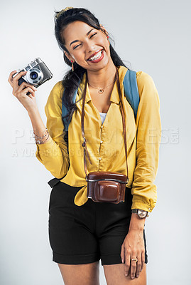 Buy stock photo Shot of a young woman wearing a backpack and holding a camera against a white background
