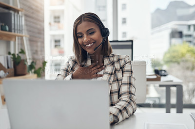 Buy stock photo Shot of an attractive young businesswoman sitting in her office and using a headset and laptop for a video call