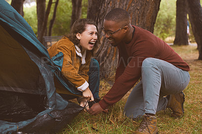 Buy stock photo Shot of a young couple working together to put up their tent