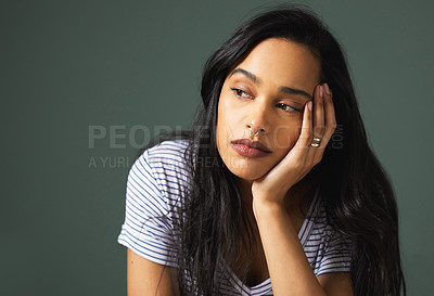 Buy stock photo Cropped shot of an attractive young woman looking depressed against a green background in studio