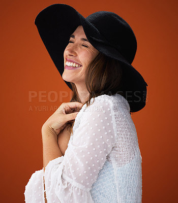 Buy stock photo Woman, smile and hat with studio for fashion with laugh, trendy and memory for outfit for expression style inspiration. Elegant, stylish and orange background with funny for laughing with gorgeous