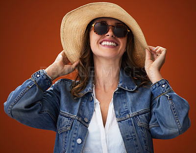 Buy stock photo Hat, happy and woman with sunglasses for fashion, holiday or travel in studio isolated on a red background. Face, smile and model with shades in casual clothes, cool and ready for vacation in Germany
