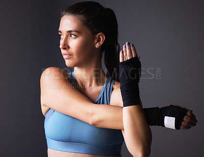 Buy stock photo Shot of a young woman stretching her arms against a grey background
