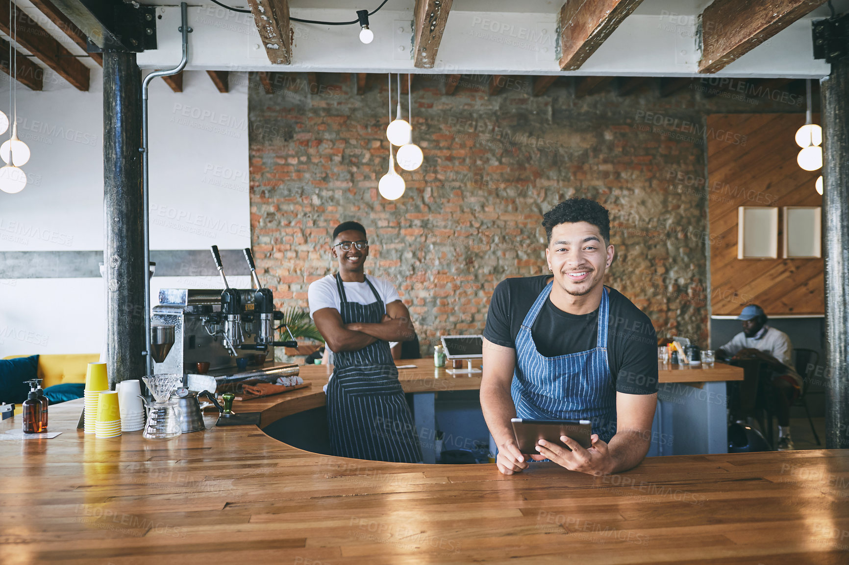 Buy stock photo Shot of two young men using a digital tablet while working in a cafe