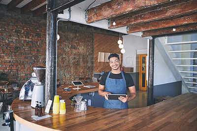 Buy stock photo Shot of a confident young man using a digital tablet while working in a cafe