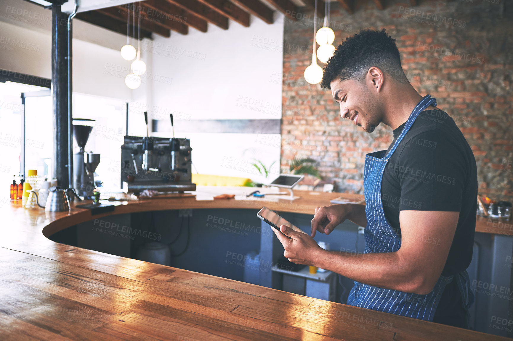 Buy stock photo Shot of a confident young man using a digital tablet while working in a cafe