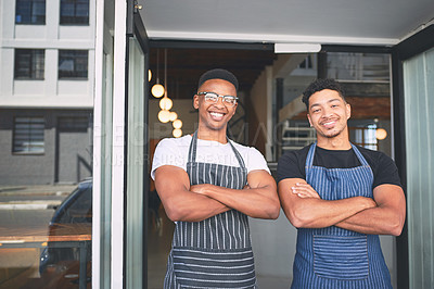 Buy stock photo Shot of two confident young men standing at the entrance of their cafe