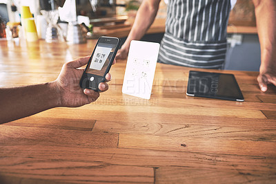 Buy stock photo Shot of a man using a smartphone to make a contactless payment in a cafe