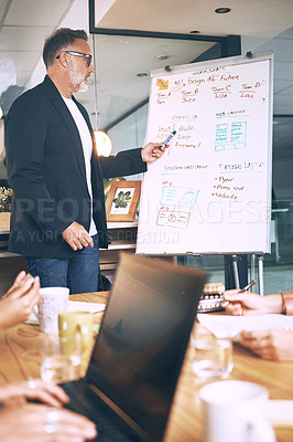 Buy stock photo Shot of a mature businessman delivering a presentation to his coworkers in the boardroom of a modern office