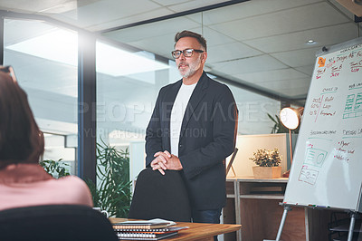 Buy stock photo Shot of a mature businessman delivering a presentation to his coworkers in the boardroom of a modern office