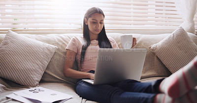 Buy stock photo Shot of a young businesswoman using her laptop to work at home while sitting in her living room