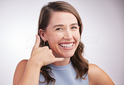 Buy stock photo Studio portrait of a young woman making a call me gesture against a grey background