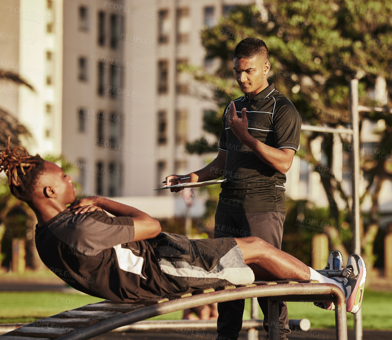 Buy stock photo Shot of a young man working out with his trainer doing crunches