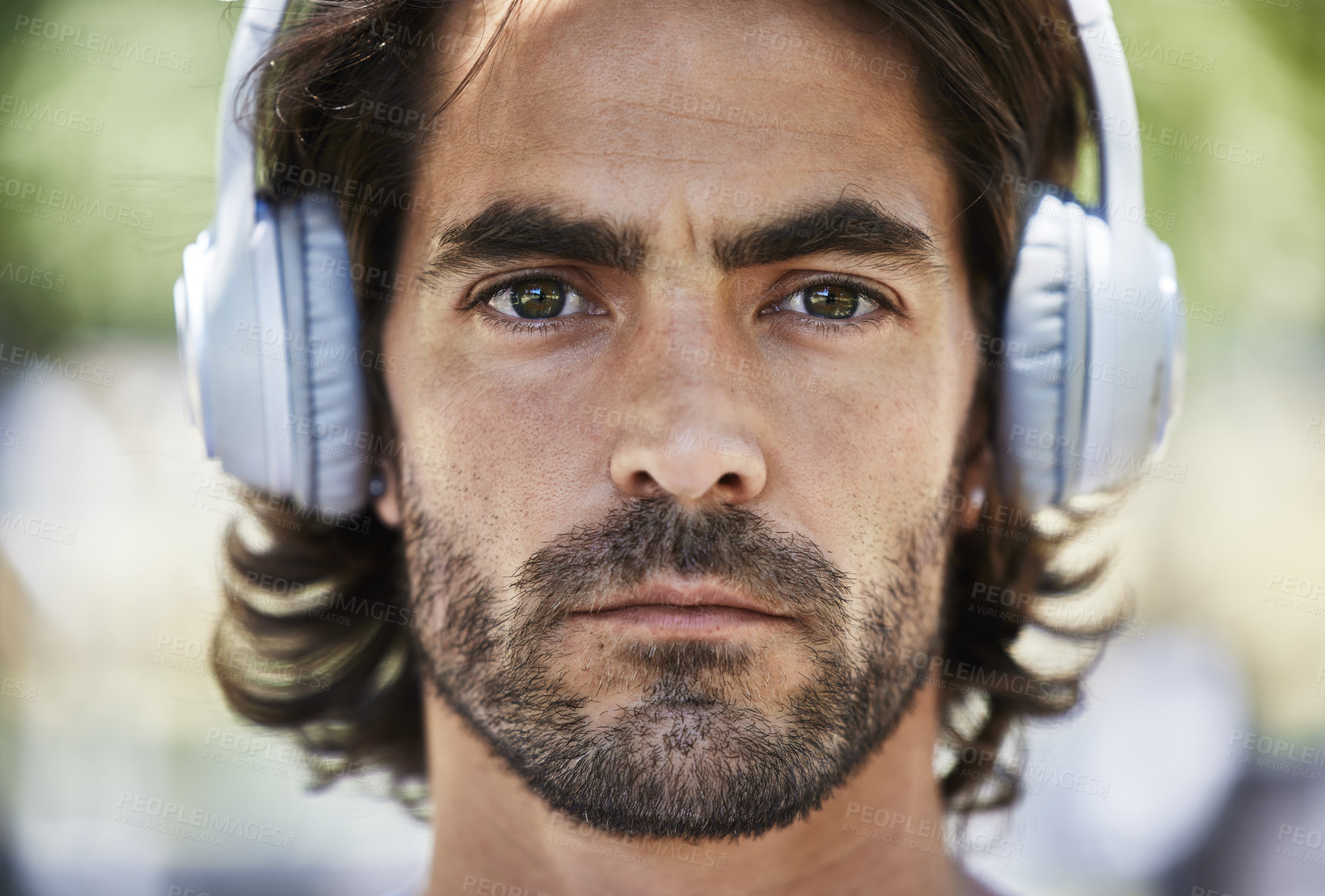 Buy stock photo Shot of a young man listening to music on his headphones outside in the park