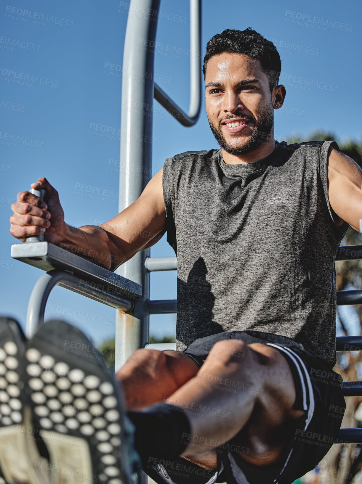 Buy stock photo Shot of a muscular young man exercising at a calisthenics park