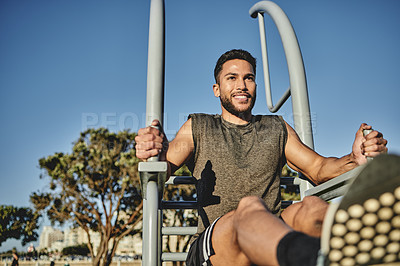 Buy stock photo Shot of a muscular young man exercising at a calisthenics park