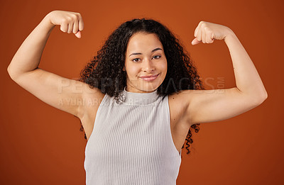 Buy stock photo Cropped portrait of an attractive young woman flexing her biceps in studio against a red background
