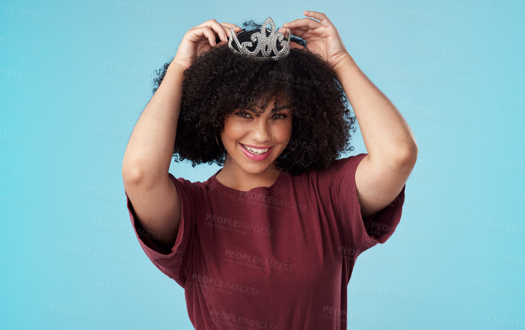 Buy stock photo Studio shot of a young woman putting a crown her head against a blue background