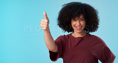 Buy stock photo Studio shot of a young woman showing thumbs up against a blue background