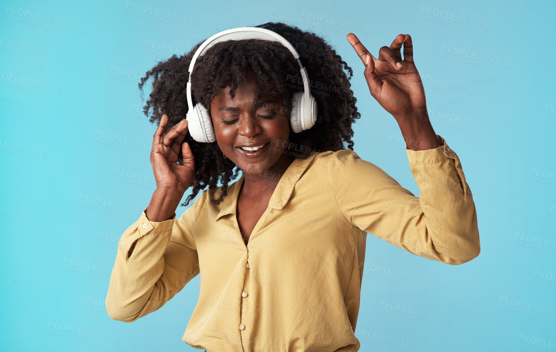 Buy stock photo Studio shot of a young woman using headphones and dancing against a blue background