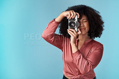 Buy stock photo Studio shot of a young woman using a camera against a blue background